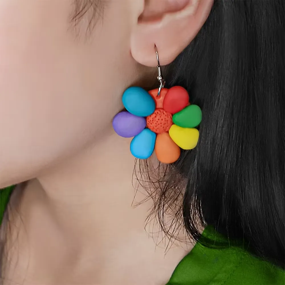 Фото в стиле жизни комплекта полимерной глины 60 цветов с handmade-серьгами в виде цветка радуги с подвеской, надетыми на ухо, демонстрирующими готовое ювелирное изделие из глины