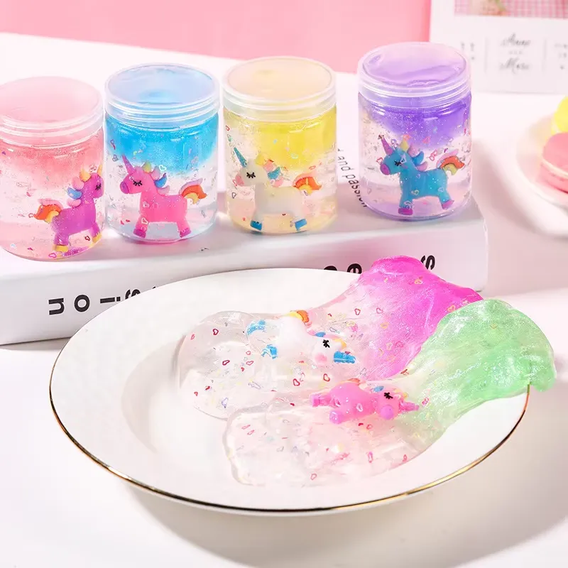 Kit de Slime Transparente para Niños en uso – los frascos están sobre un libro mientras el slime rosa, transparente y verde se vierte en un plato blanco para jugar.