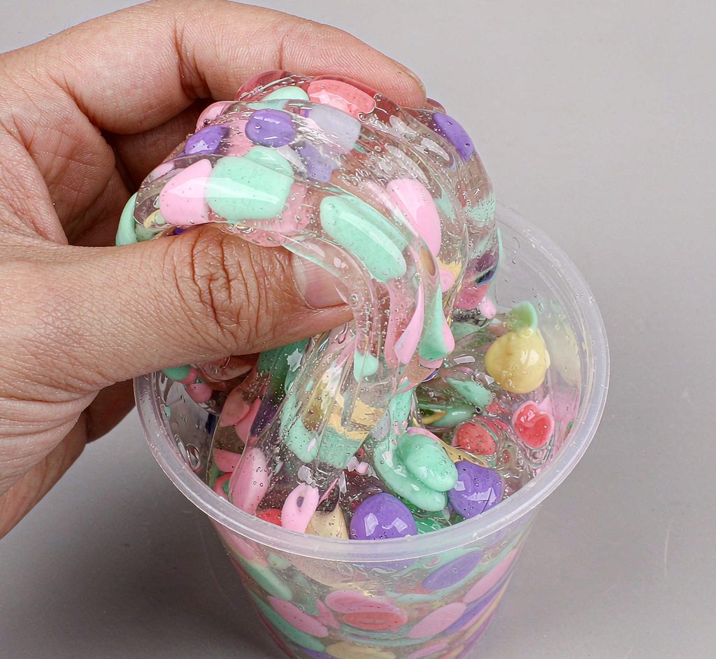 Colorful Slime Close-Up In Clear Cup Close-up of glossy colorful slime being stretched inside a clear cup