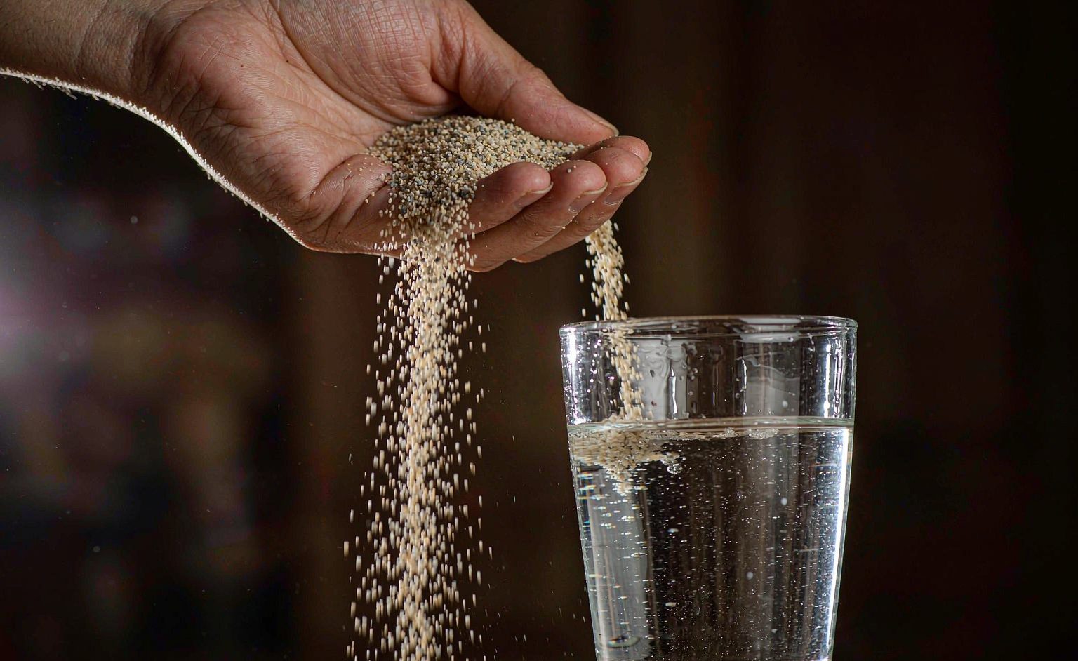 Magic sand being poured into water while staying dry in a clear container